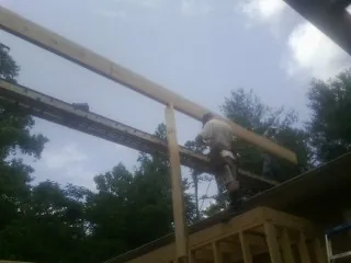 Carpenter setting a ridge beam over a new addition frame — Ice Dam Removal by Roofing Brothers in Holliston