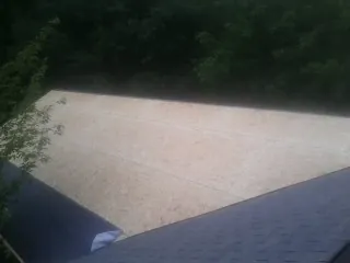 New OSB roof sheathing installed beside an existing shingle roof in Holliston