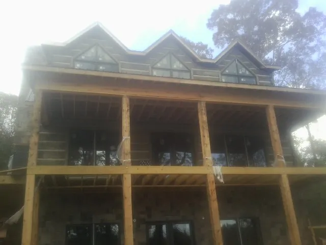 Dormers and porch framing on a large log home under construction — Roof Coating work by our crew in Holliston