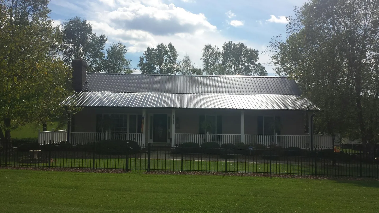 Gray metal roof on a brick ranch with a full width front porch — Gutter Guard Installation work by our crew in Holliston